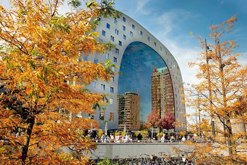A modern building with a large arched glass facade, surrounded by autumn trees. 5