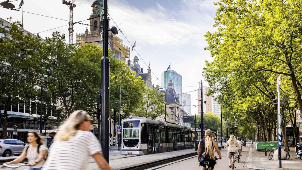 A tram on tracks, pedestrians, cyclists, and urban buildings. 4