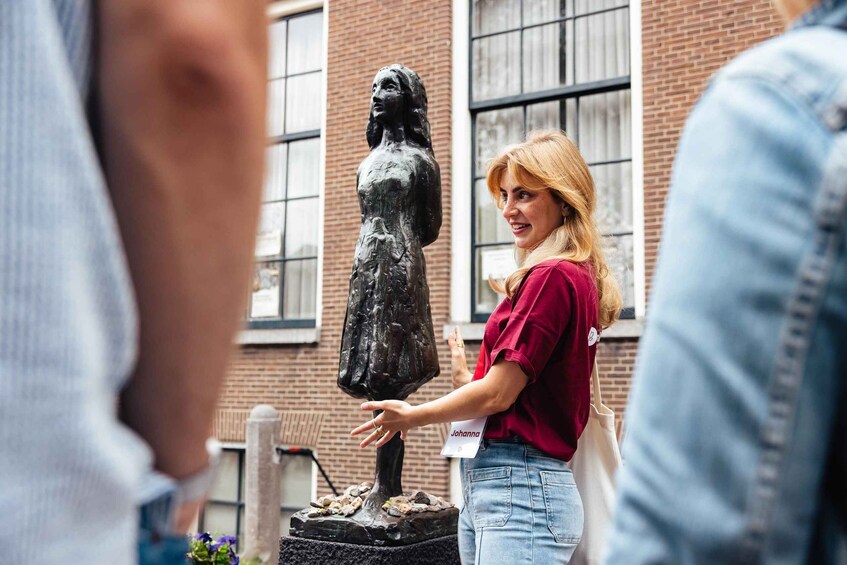 A person standing next to a statue in an outdoor setting with brick buildings in the background. 4