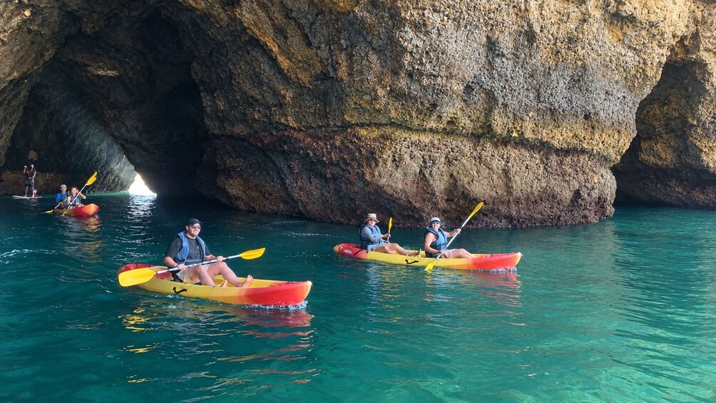 People kayaking in a cave with clear blue water. 3