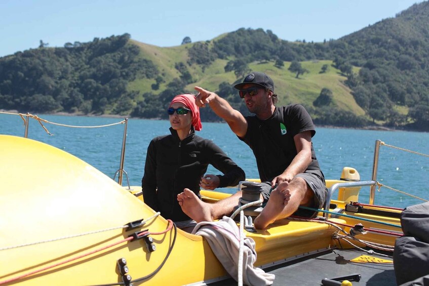 Two people on a yellow boat with a mountainous landscape in the background. 2