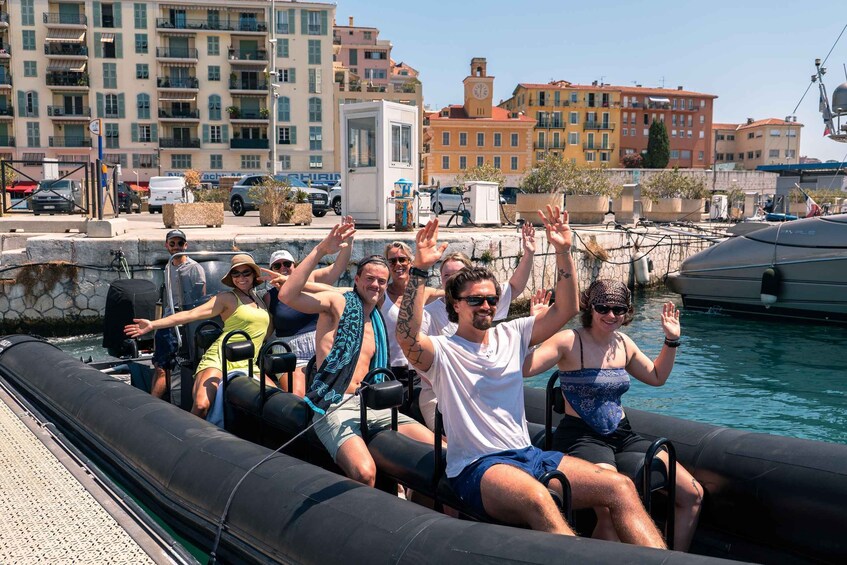 Des personnes à bord d’un bateau, les bras levés, une marina et des bâtiments en arrière-plan. 5