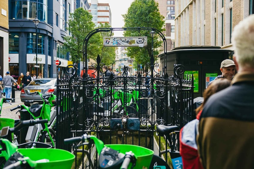 A street with a bike parking rack filled with bicycles and green baskets. 5