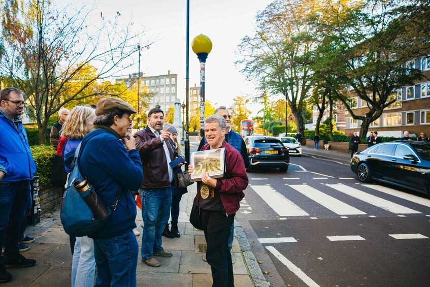 A group of people standing on a sidewalk, some holding books or pamphlets. 2
