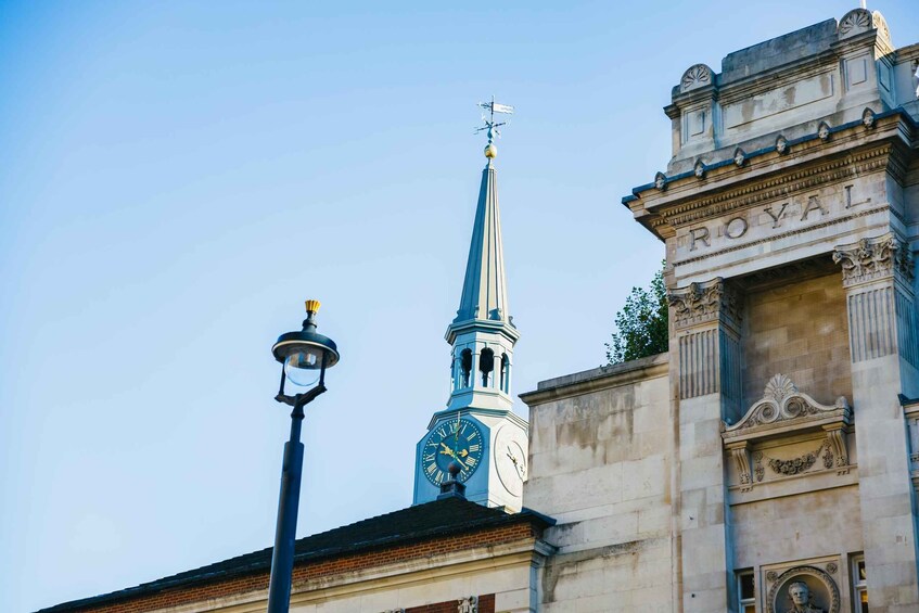 A clock tower with a weather vane and the word "ROYAL" on a building. 3