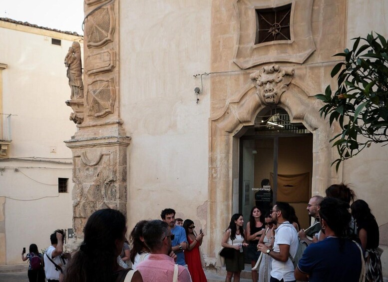 A group of people gathered outside a building with a stone facade and a decorative archway. 4