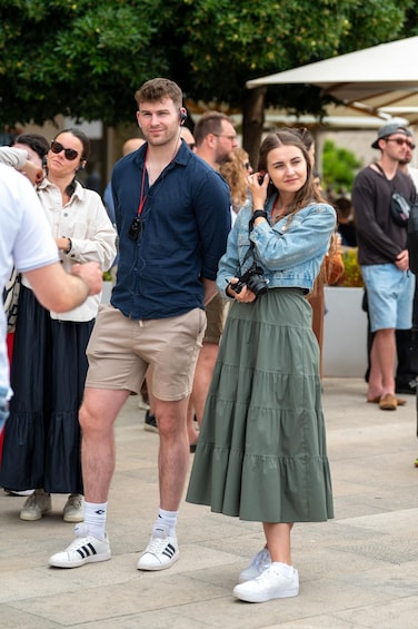 A man in a blue shirt and shorts standing next to a woman in a green skirt and denim jacket. 5