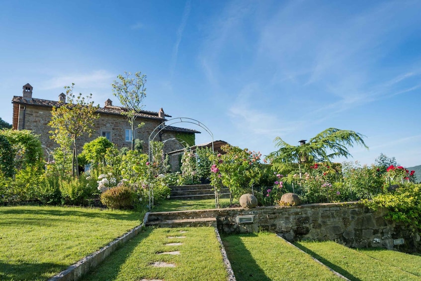 Une maison en pierre avec un jardin, un mur de pierre et un ciel bleu dégagé. 4