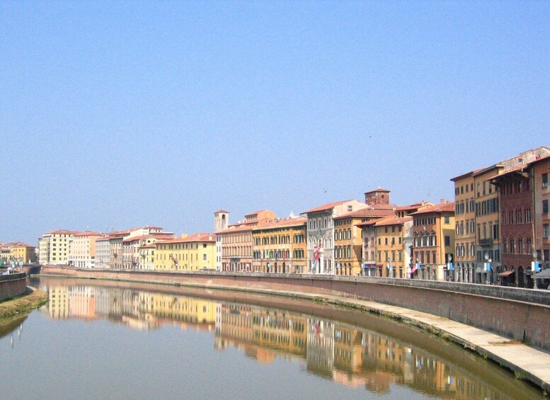 A calm river reflecting buildings with red roofs. 1