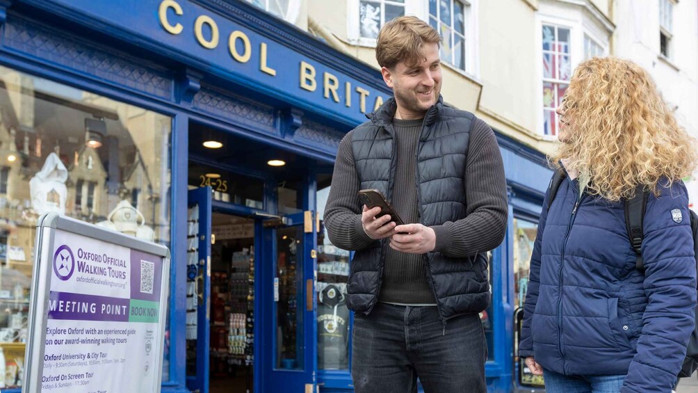 Two people standing outside a store with a sign for walking tours. 3
