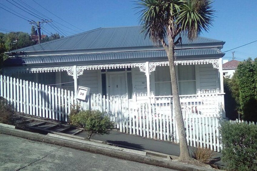 A white house with a porch, a palm tree, and a white picket fence. 4