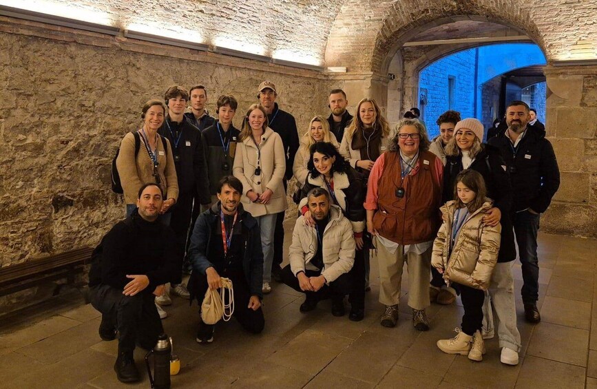 A group of people in a stone-walled corridor with an arched doorway. 5