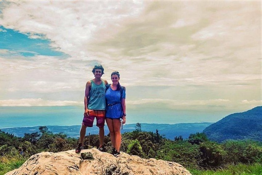 Två personer som står på en klippa med ett kustlandskap i bakgrunden. 4