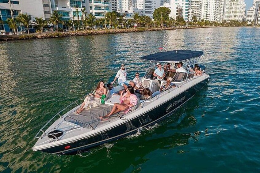A speedboat with passengers on a calm body of water, surrounded by a city skyline. 1
