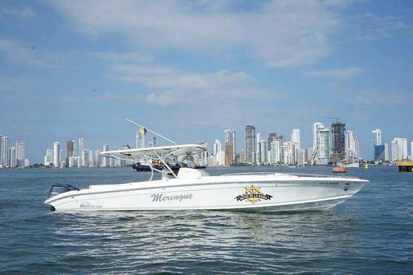 A white speedboat named 'Merengue' on water with a city skyline in the background. 2