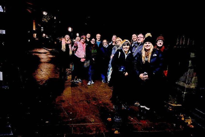 A group of people standing on a wet pavement at night. 5
