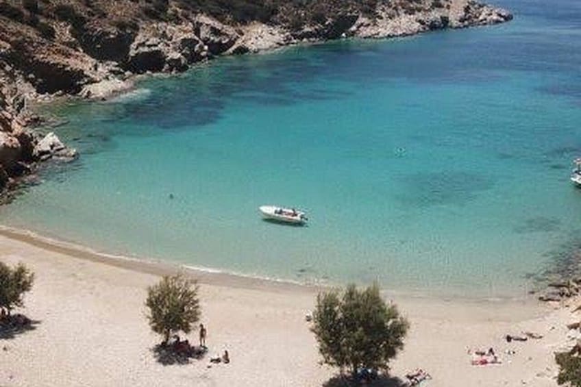 Ein Strand mit klarem türkisblauem Wasser, einem Boot und einigen Personen. 3