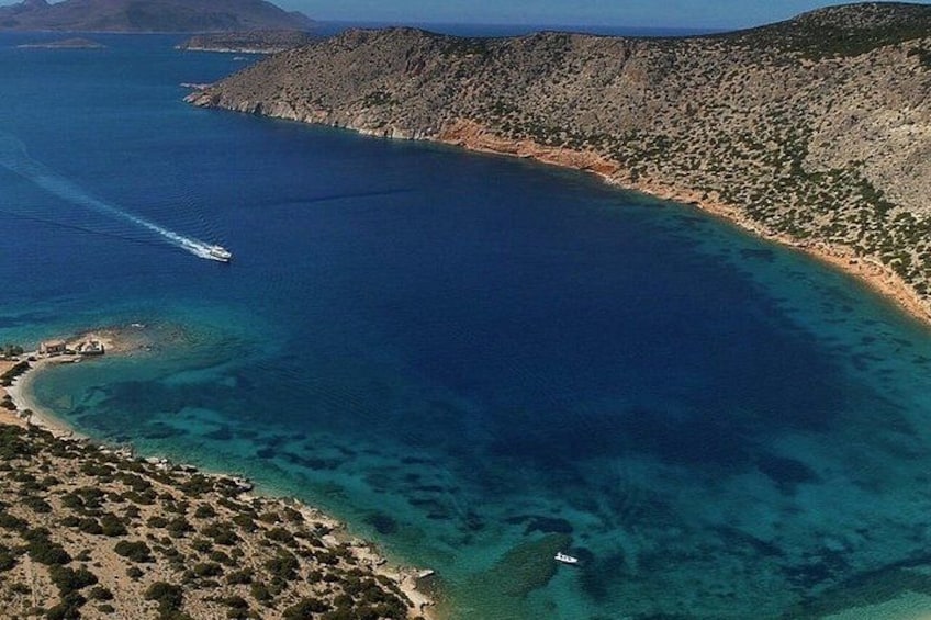 Eine Küstenlandschaft mit einem Boot auf dem Wasser, einem Sandstrand und felsigem Gelände. 2