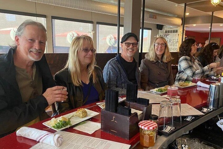 Eine Gruppe von Menschen speist in einem Restaurant mit rotem Tisch, einer Speisekarte und einem Einlegeglas. 4