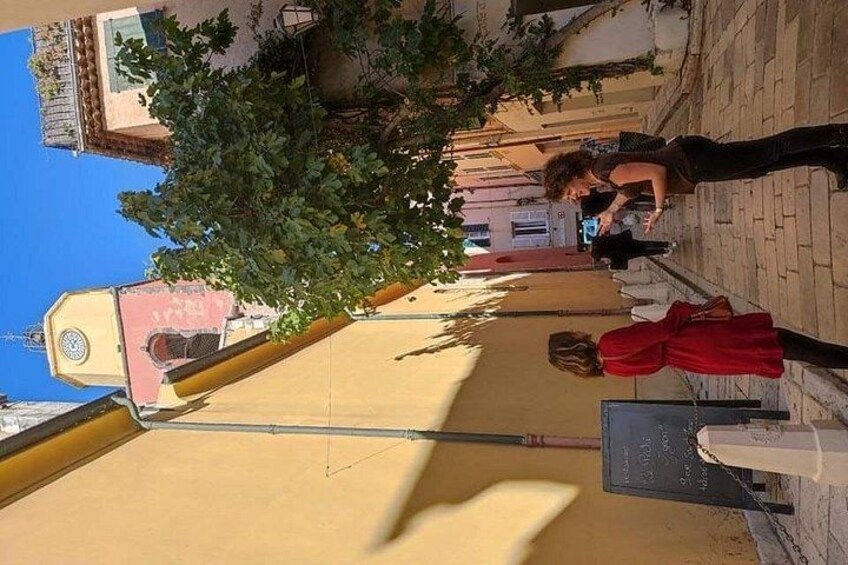 A street with a yellow building, a tree, and a person in a red dress. 2