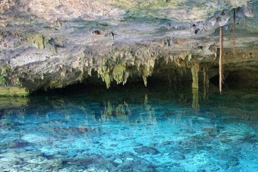 A cave with clear blue water and stalactites. 1