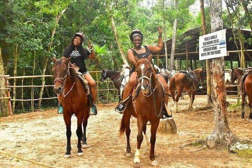 Two people riding horses in an enclosed area with a sign indicating a weight limit for horses. 5