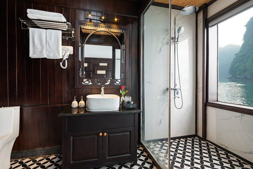 A bathroom with a marble sink, dark wood cabinets, a large mirror, and a shower. 4