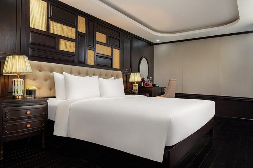 A large bed with white linens, dark wood headboard, and two bedside tables with lamps. 5