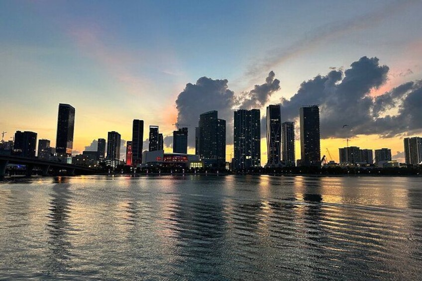 Un horizonte urbano al atardecer, con edificios altos reflejándose en el agua. 3