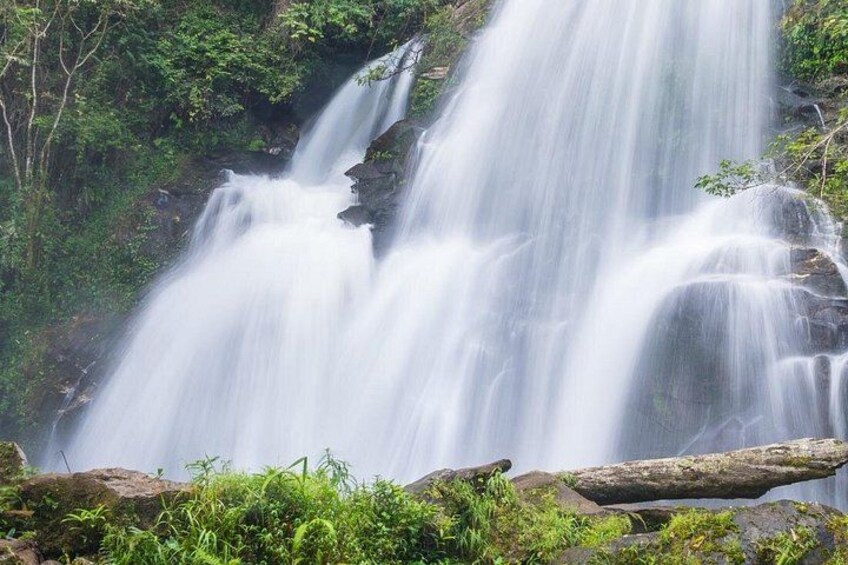 A waterfall cascading over rocks surrounded by lush greenery. 2