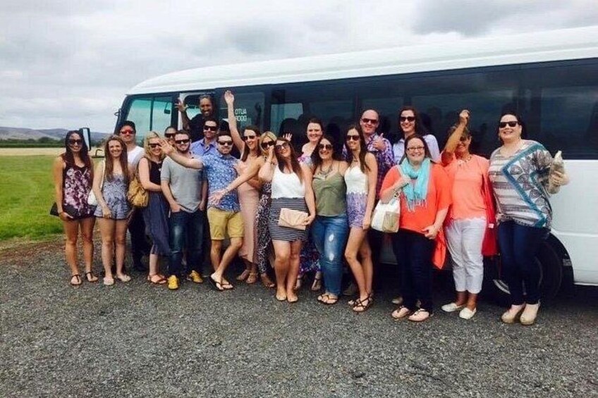 A group of people standing in front of a white bus. 3