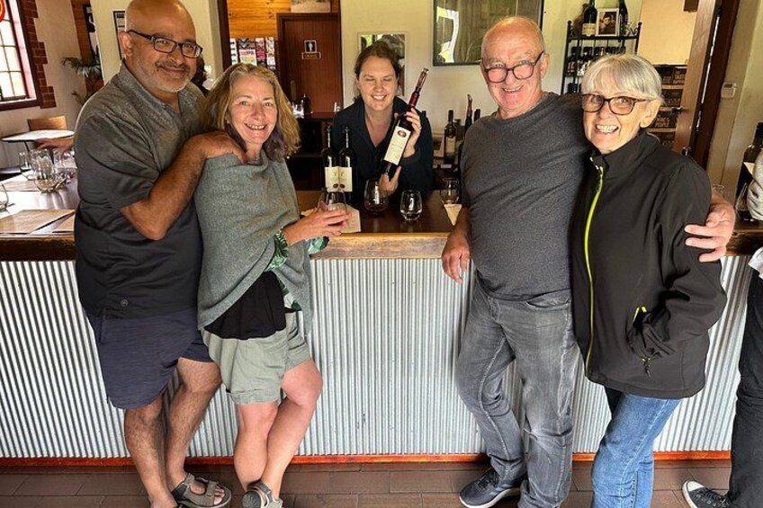 A group of people standing at a bar with bottles and glasses. 1