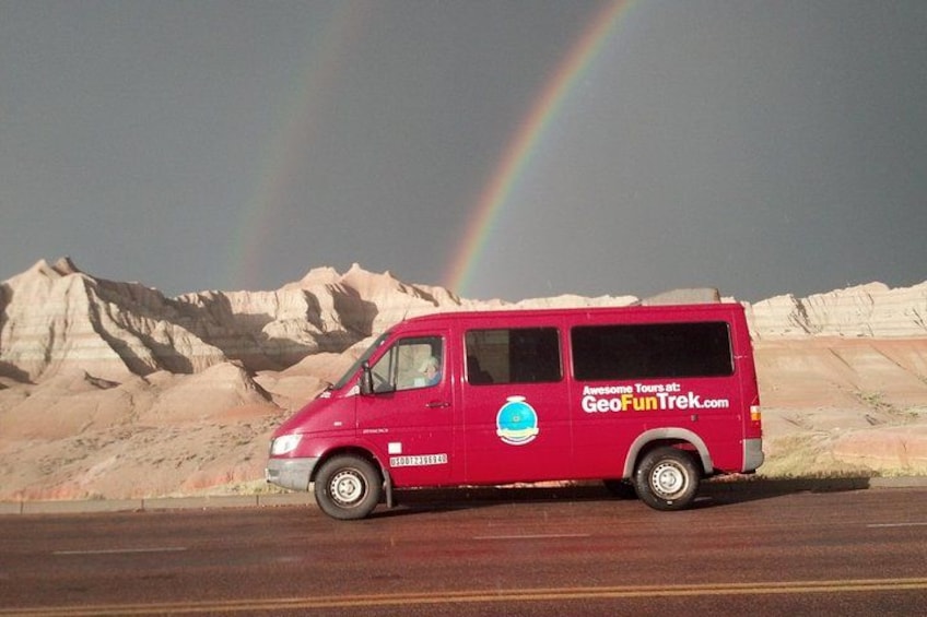 Una camioneta roja con un arcoíris al fondo. 2