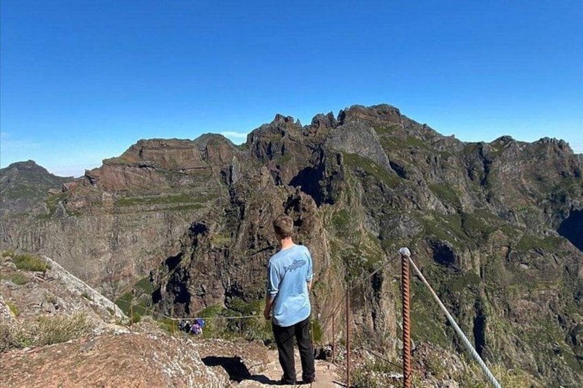 En person står på en klippe med udsigt over et bjergrigt landskab. 5
