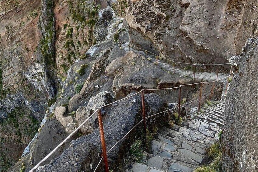 A rocky mountain trail with stone steps and metal railings. 2