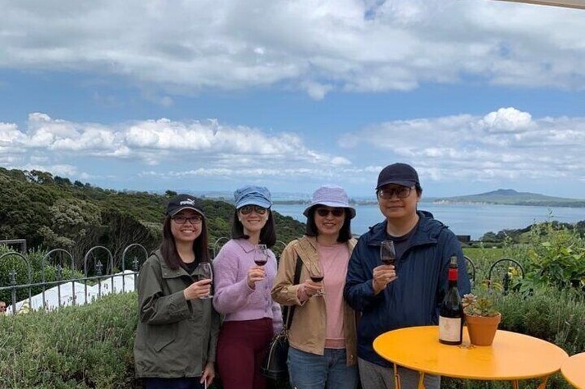 Four people standing by a table with a bottle of wine and a potted plant. 3