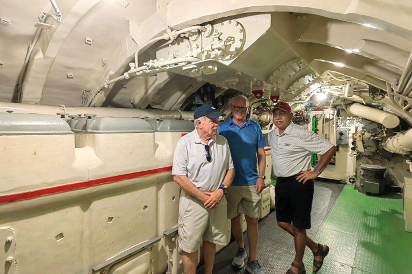 A group of people inside a submarine, standing near the control panel. 5