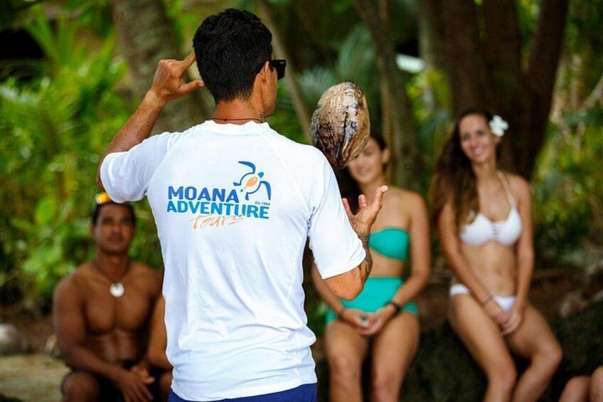 En person i hvid t-shirt med teksten 'MOANA ADVENTURE', der står med en hat på hovedet. 2