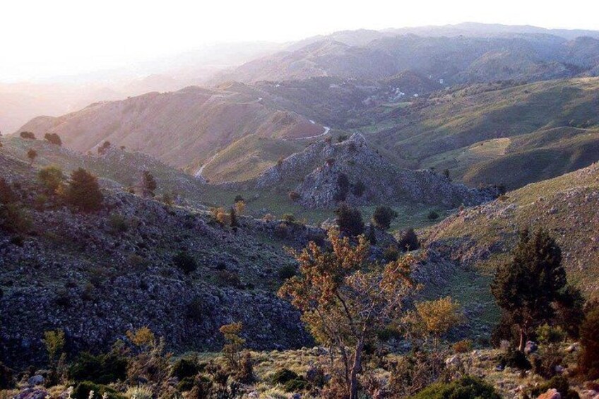 Eine gebirgige Landschaft mit felsigem Untergrund, spärlicher Vegetation und weit entfernten Hügeln. 5