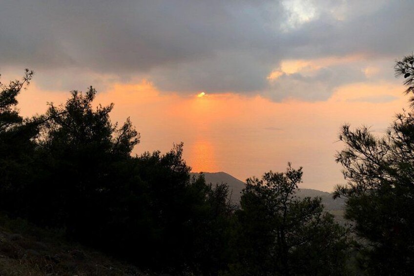 Ein Sonnenuntergang mit Wolken, Bäumen und einem Berg im Hintergrund. 4