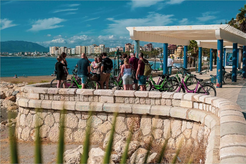 Un grupo de personas junto al muelle, con bicicletas aparcadas cerca y un paisaje urbano al fondo. 3