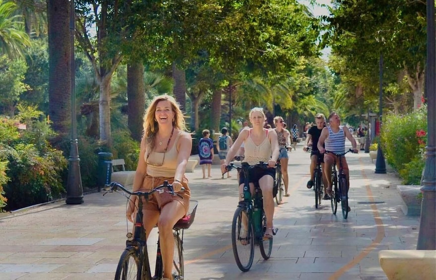 Un grupo de personas andando en bicicleta por un camino bordeado de árboles. 2