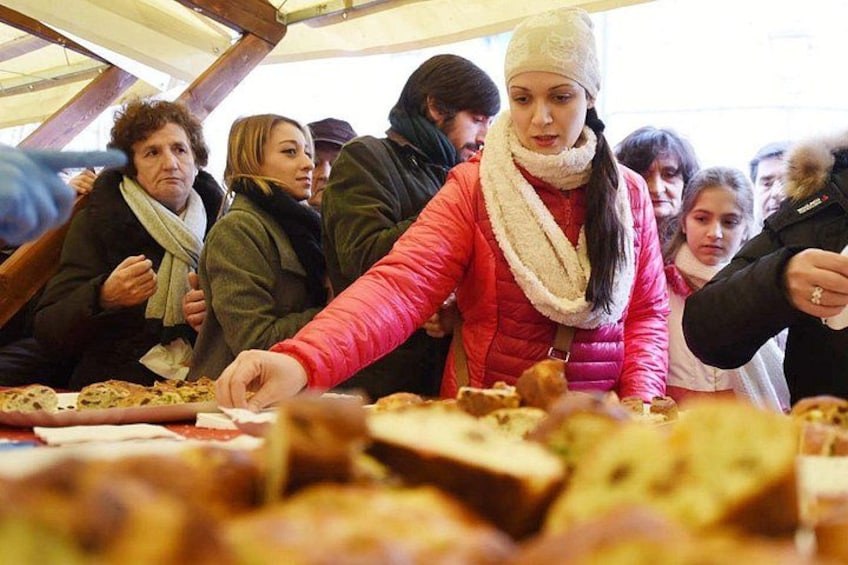 A group of people at a food stall with various dishes. 1