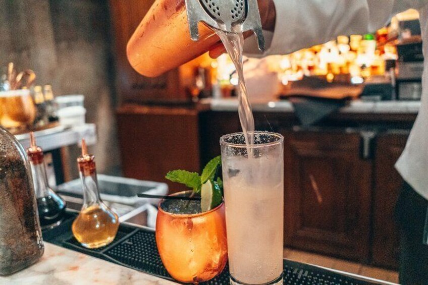 A bartender pouring a drink into a tall glass. 4