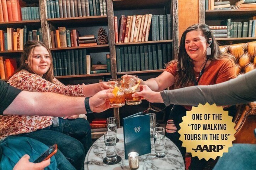 A group of people toasting with drinks in a library setting. 1