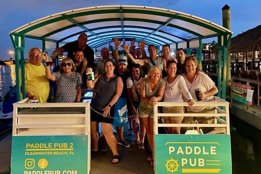 A group of people on a paddle boat with a covered structure, docked at a waterfront location. 4