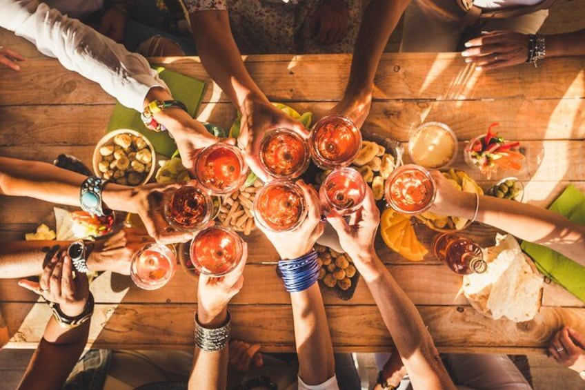 Un grupo de personas alrededor de una mesa de madera con bebidas y aperitivos. 2