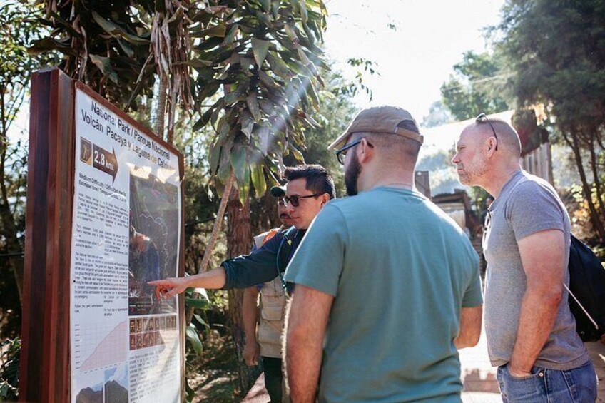 A group of people at a park information board with a map and text. 2