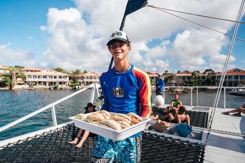 Una persona sirviendo comida en un barco, con el paisaje costero de fondo. 3