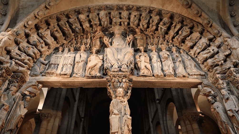 A detailed stone carving of a religious scene with figures in various poses, set within an arched structure. 4